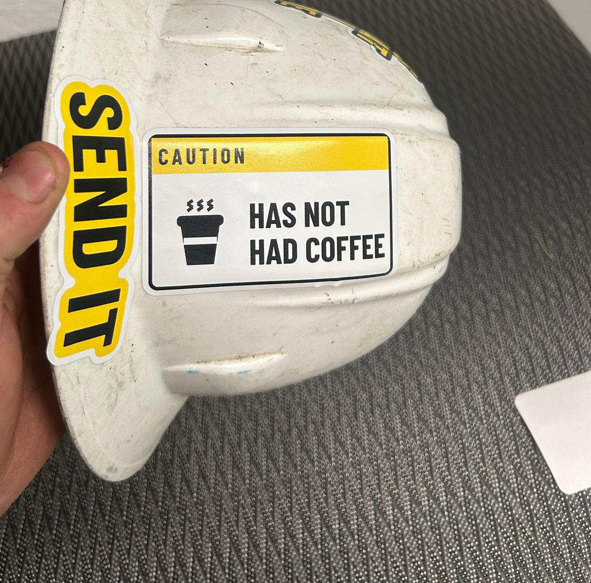 Has Not Had Coffee and Send It decals on a real, beat-up white hard hat