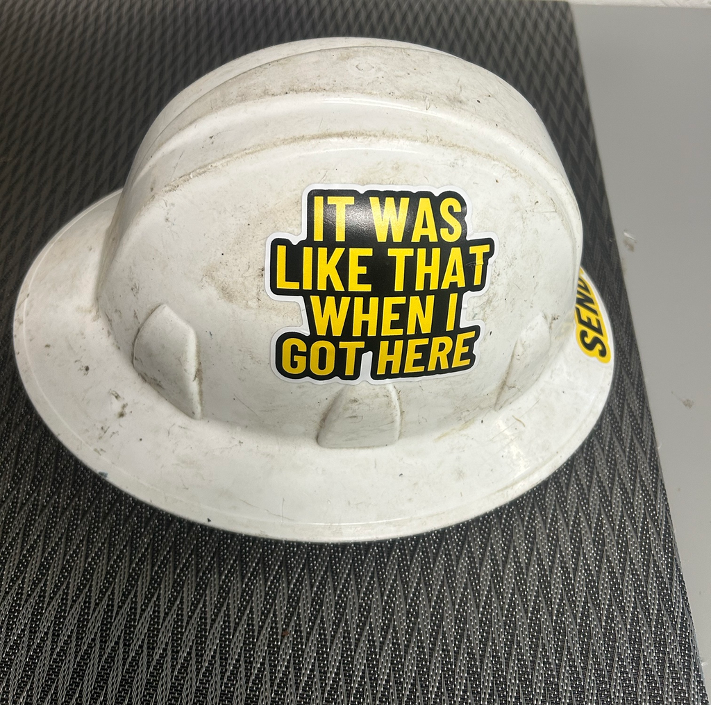 It Was Like That When I Got Here decal on the side of a real, dirty white hard hat