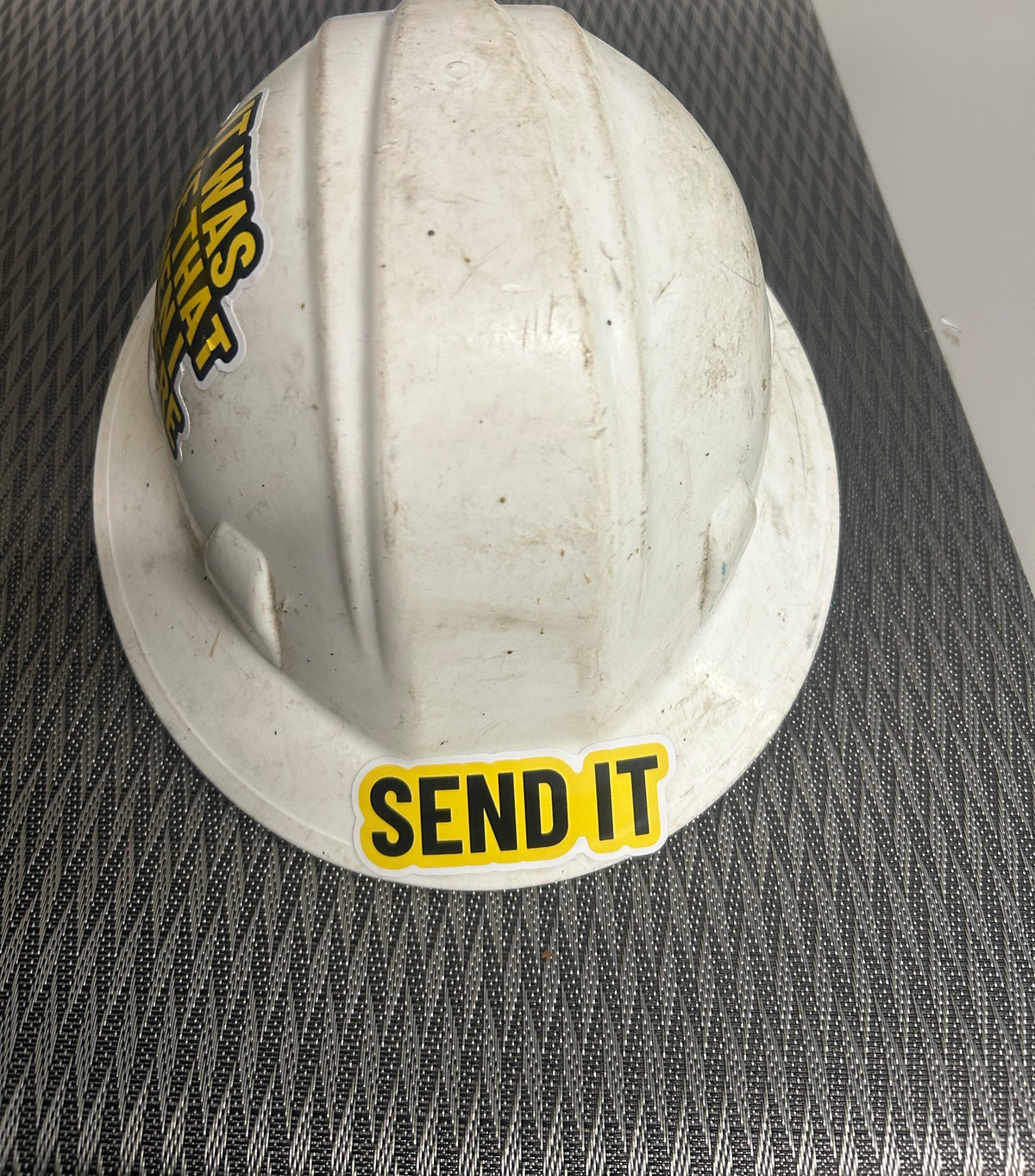 Send It decal on the brim of a real, dirty white hard hat